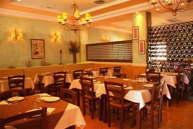 Un restaurante con mesas y sillas y una pared de botellas de vino.