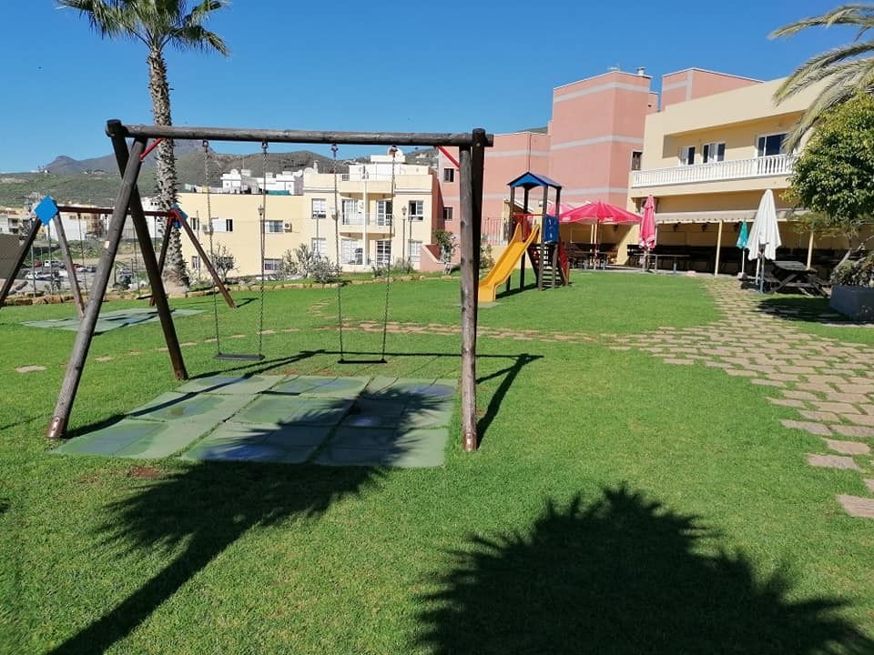 Un patio de juegos con columpios y un tobogán en un parque
