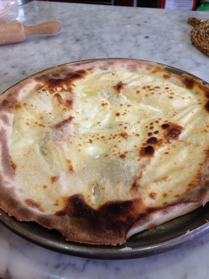 Una pizza está colocada en una sartén sobre una mesa.