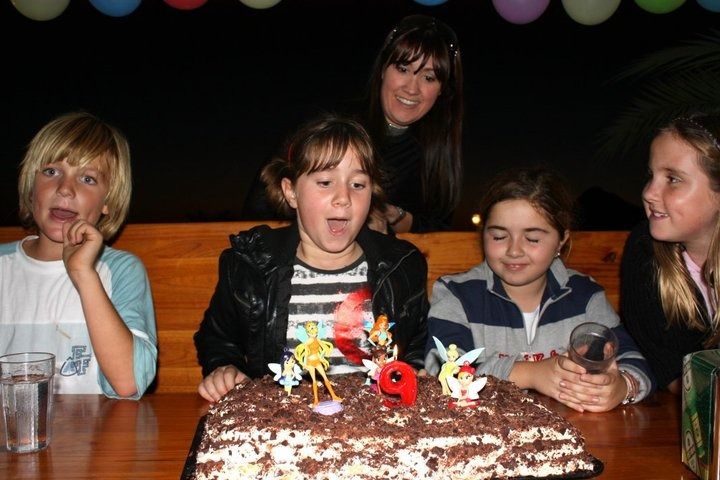 Una niña soplando las velas de un pastel de cumpleaños
