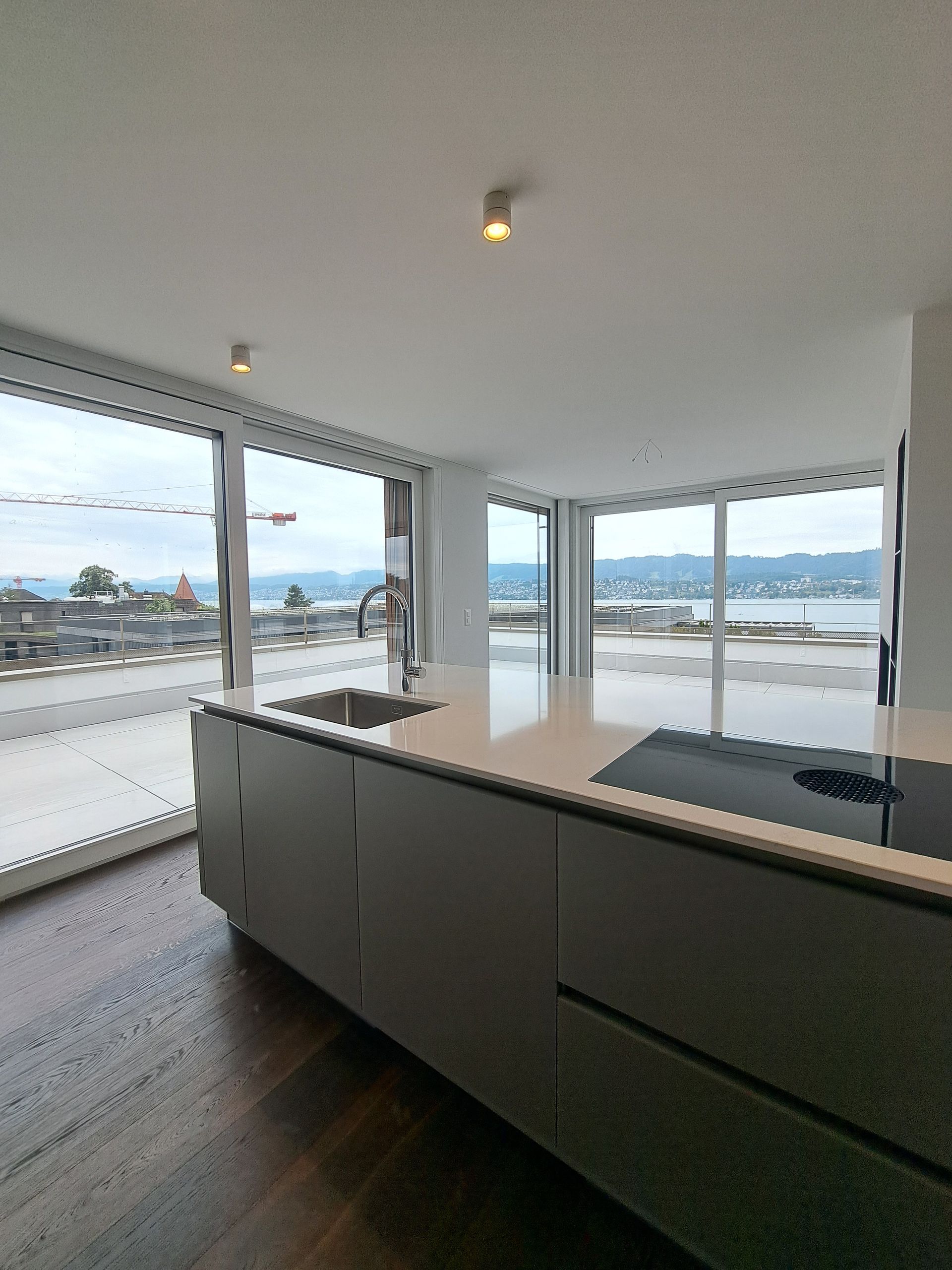 Moderne Küche mit Kochinsel, große Fenster mit Blick auf See und Stadt.