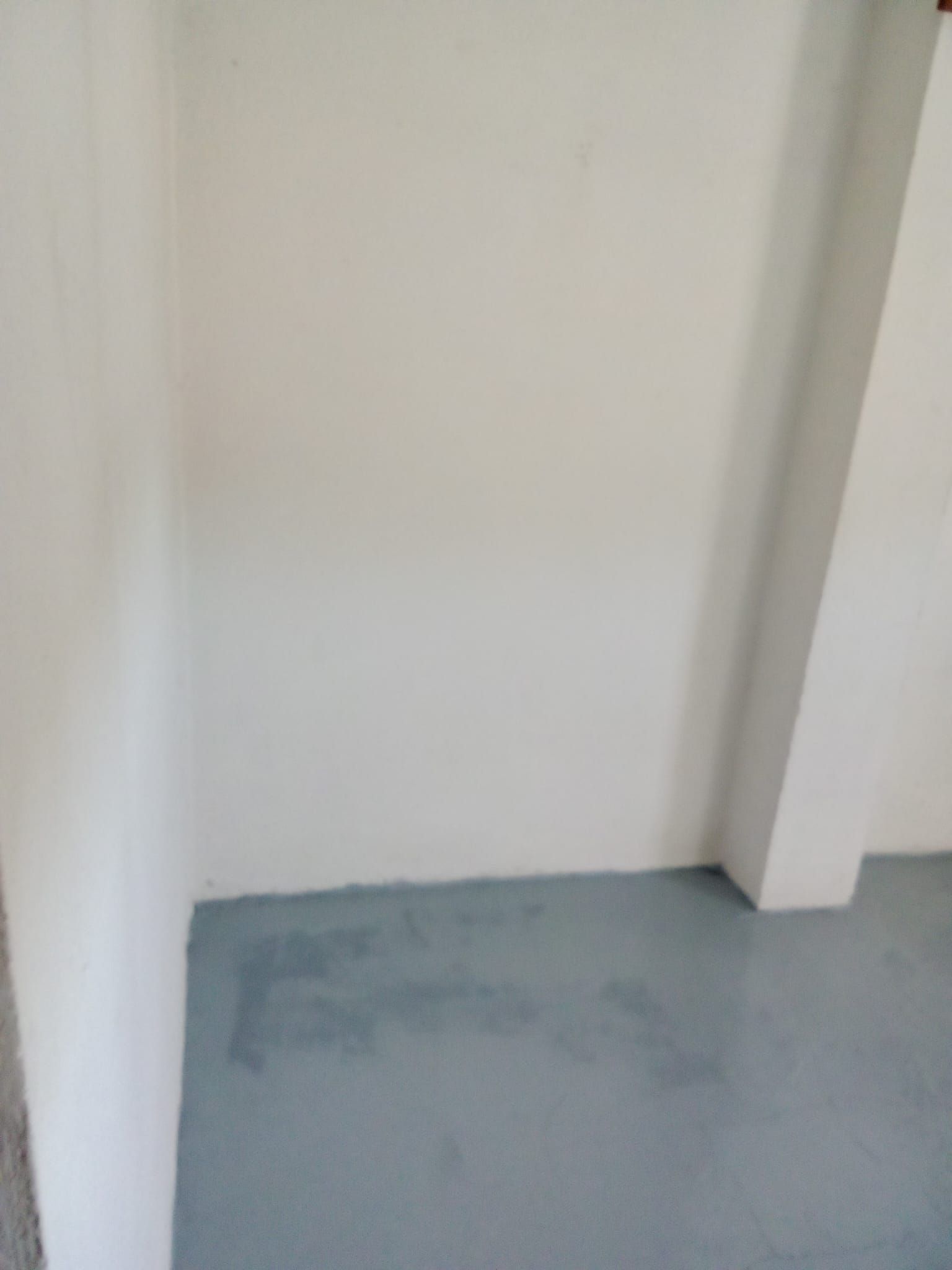 Una habitación vacía con una pared blanca y un suelo azul.