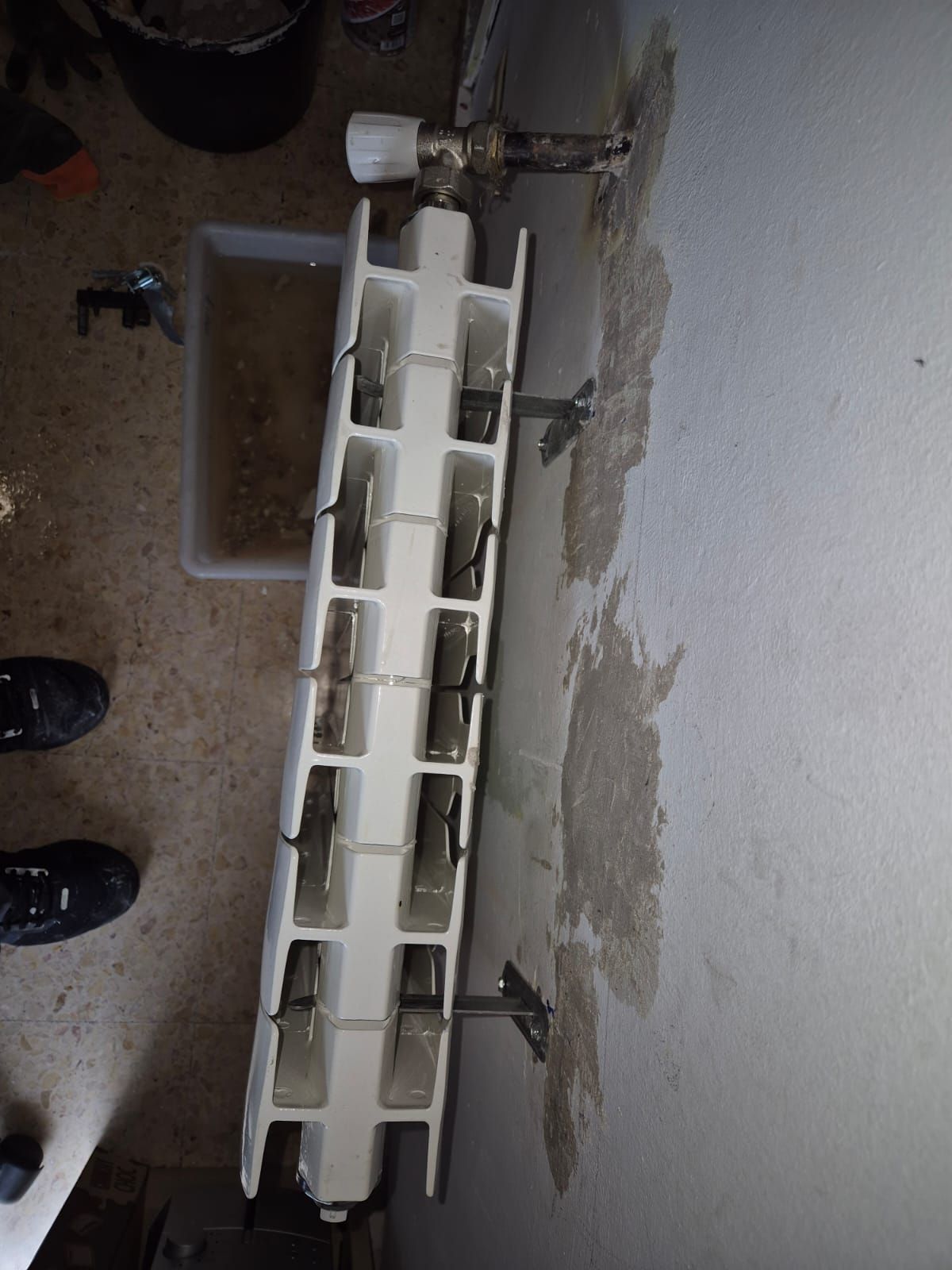 Un radiador blanco está en el suelo al lado de una pared.