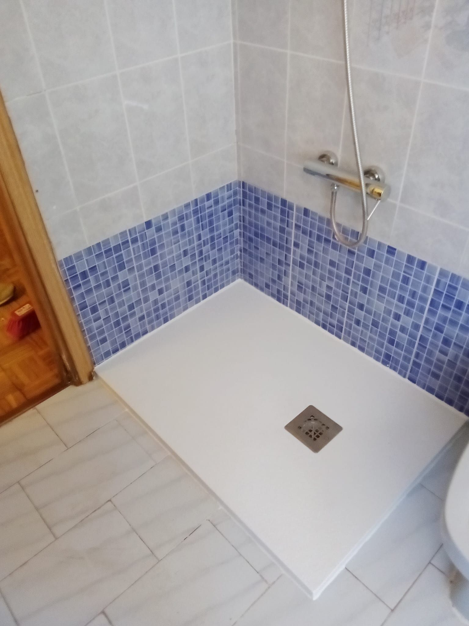 Una cabina de ducha en un baño con azulejos azules y blancos.