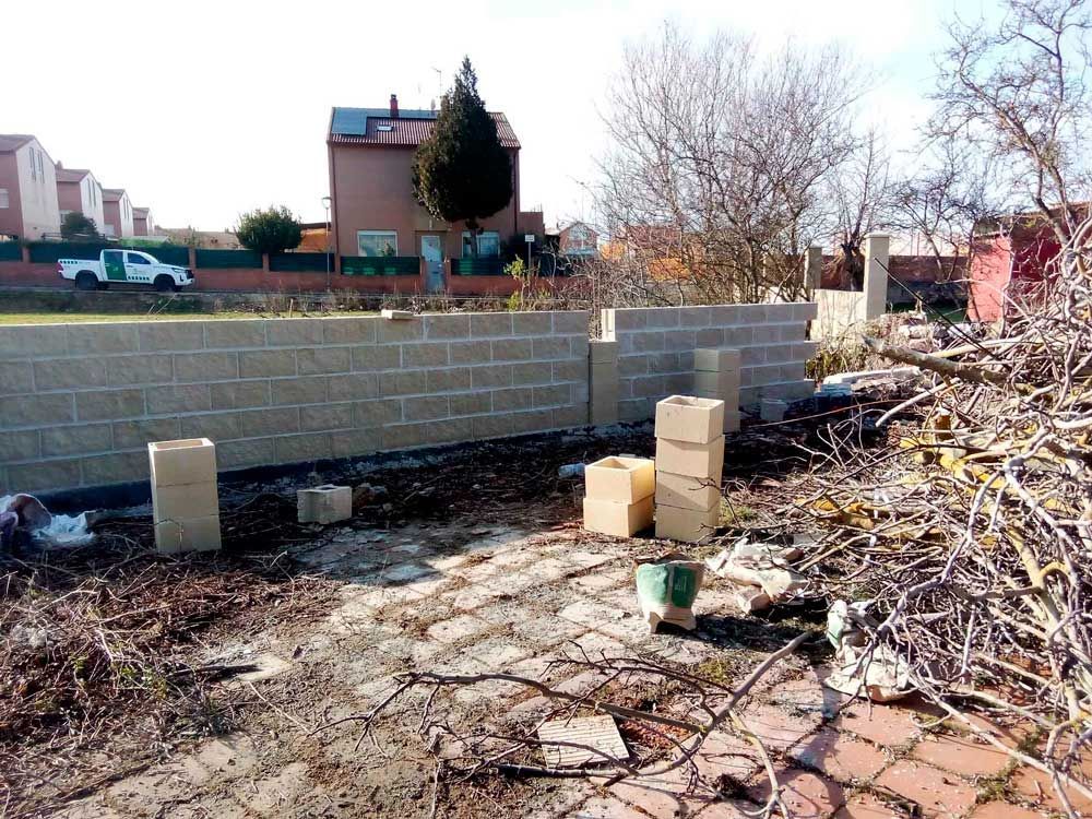 Se está construyendo un muro de ladrillos en el patio trasero de una casa.