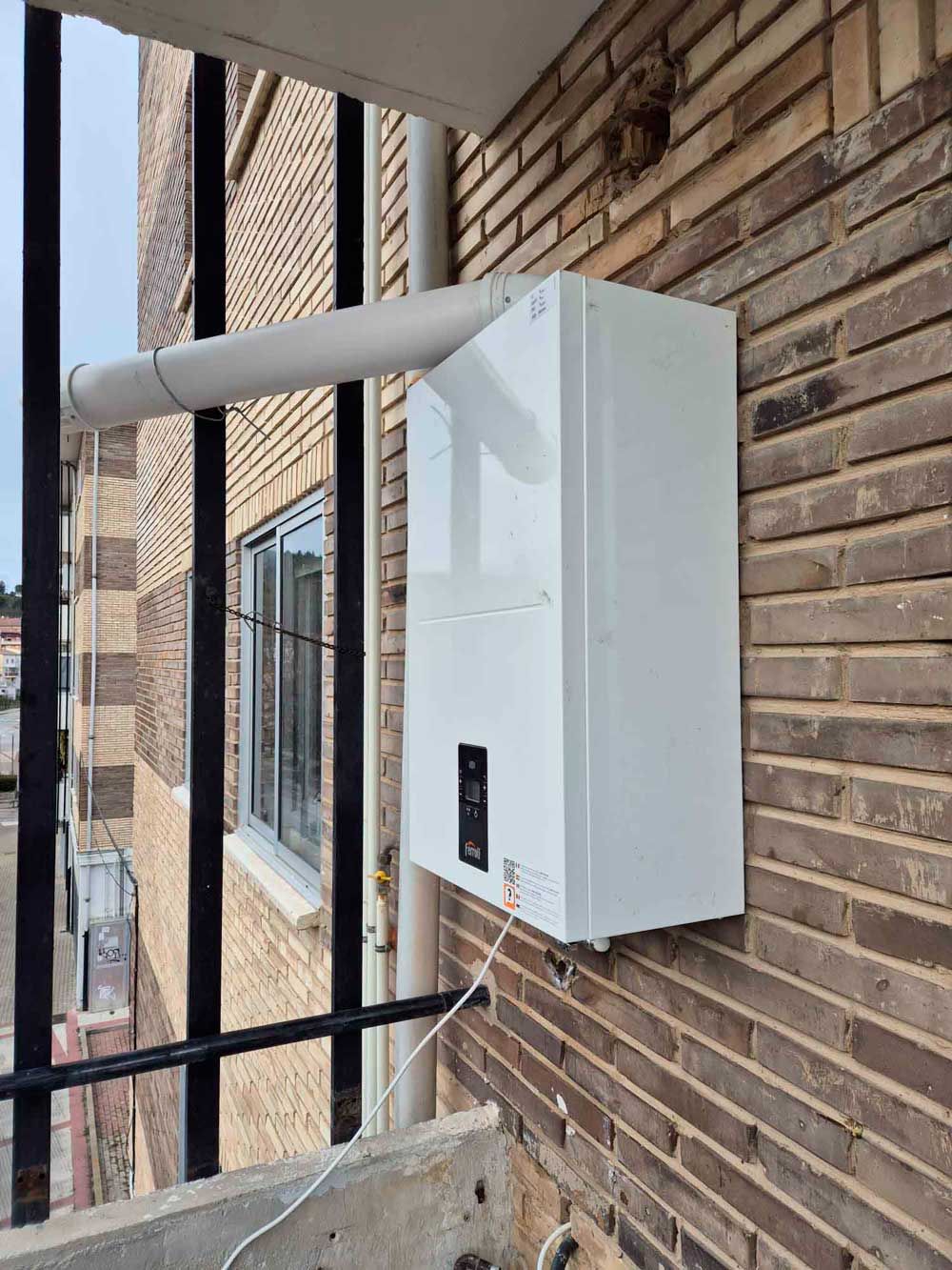 Una caja blanca está montada en el costado de un edificio de ladrillo.