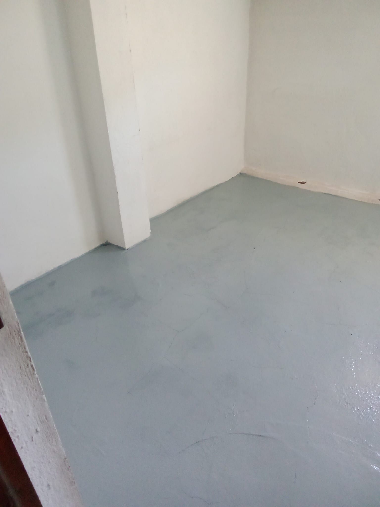 Una habitación con suelo gris y paredes blancas.