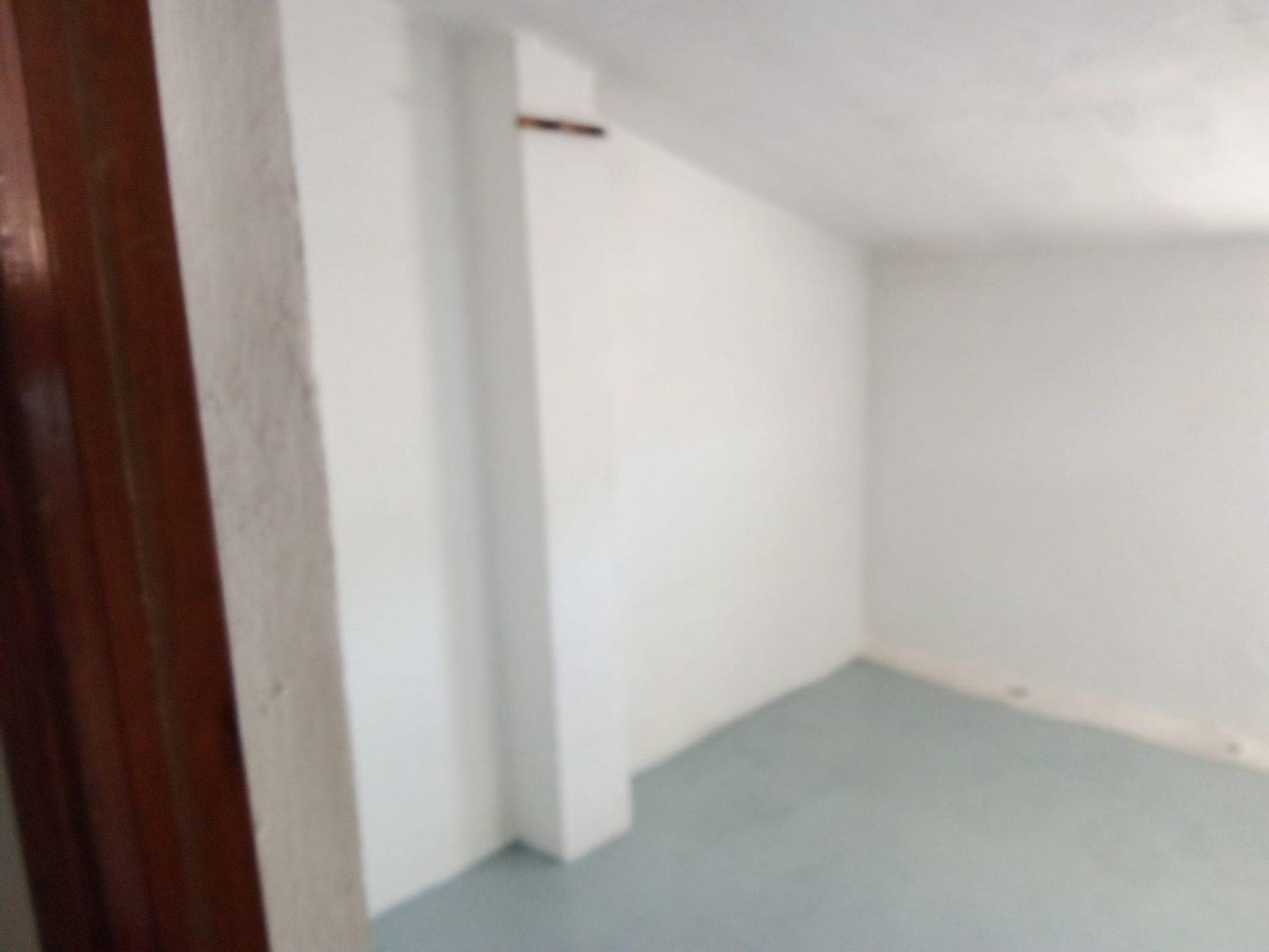 Una habitación vacía con paredes blancas y suelo azul.