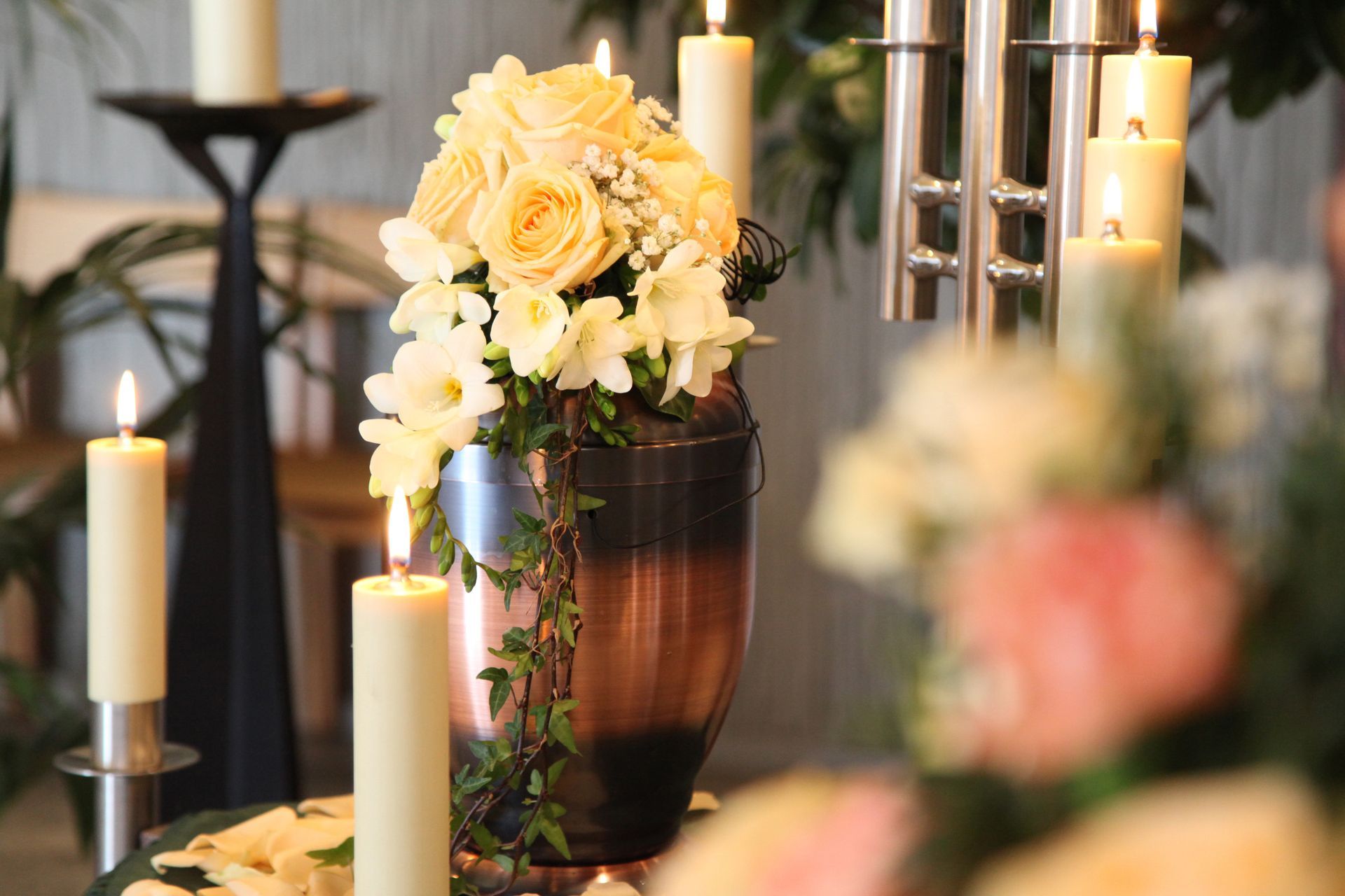 Élégante composition florale avec des roses crème et des bougies sur une table, éclairée doucement à l'intérieur.