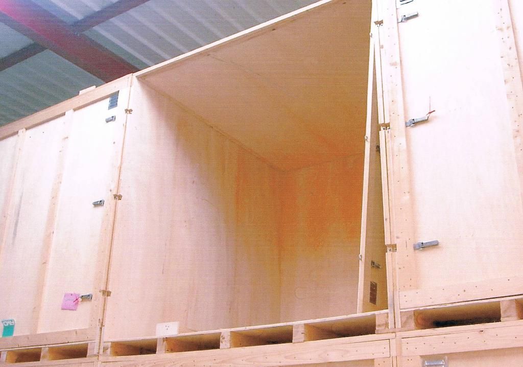 Des caisses d'expédition en bois empilées dans un entrepôt, dont une ouverte.