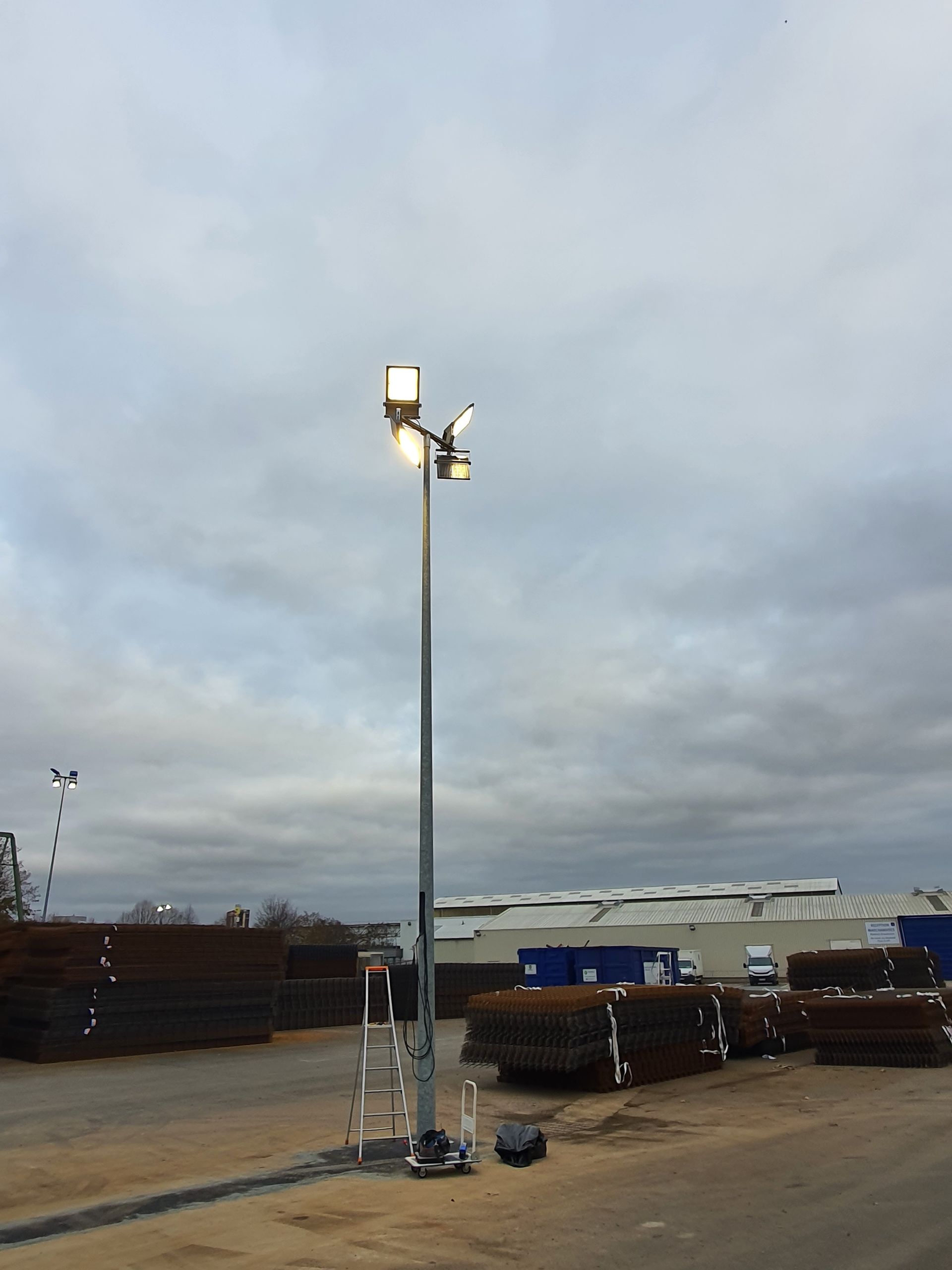 Projecteur sur un grand poteau dans une zone industrielle extérieure.