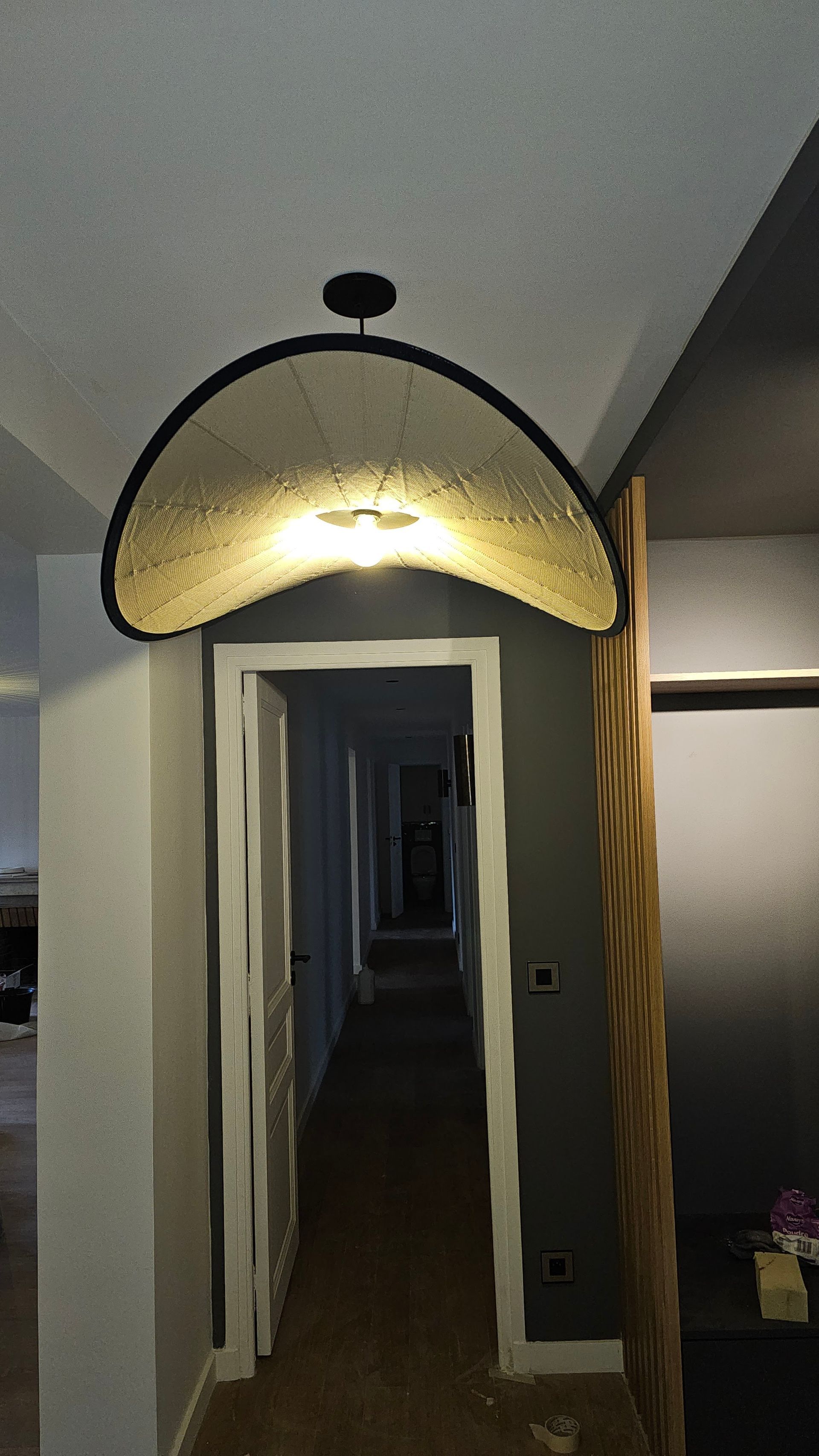 Couloir avec un luminaire décoratif en arc au-dessus d'une porte donnant sur un long couloir.