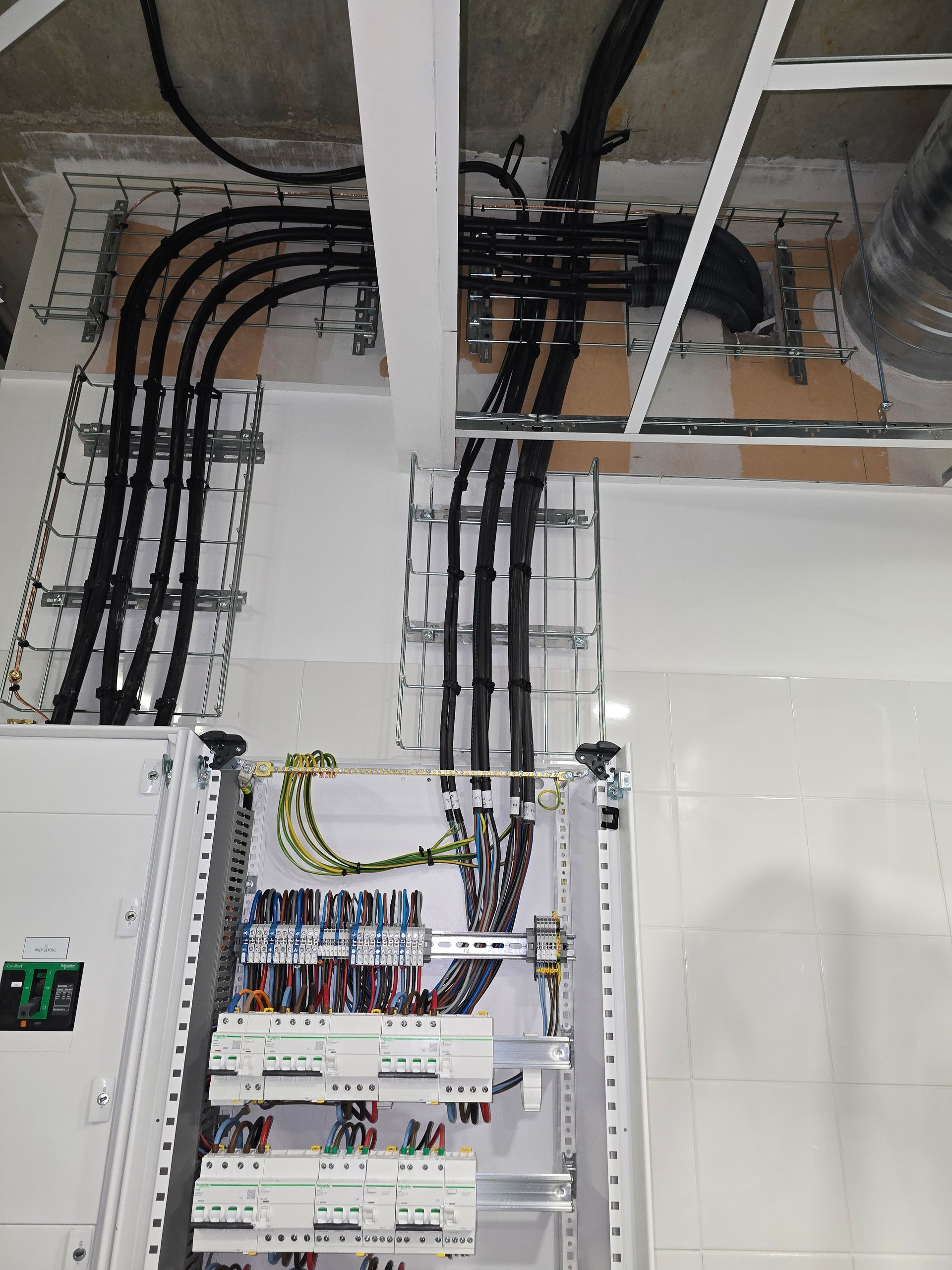 Réseau de câbles électriques sur chemin de câble avec raccordement à un tableau électrique.