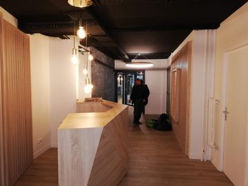 Accueil d'une entreprise, couloir blanc moderne avec lambris et ampoules suspendues.