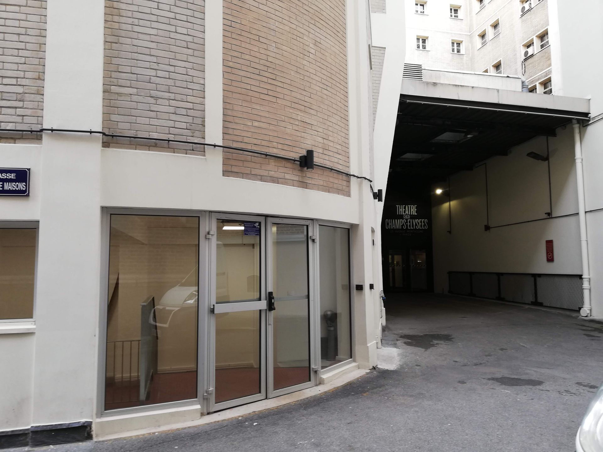 Entrée de résidence avec porte vitrée et passage couvert vers le Théâtre des Champs-Élysées.