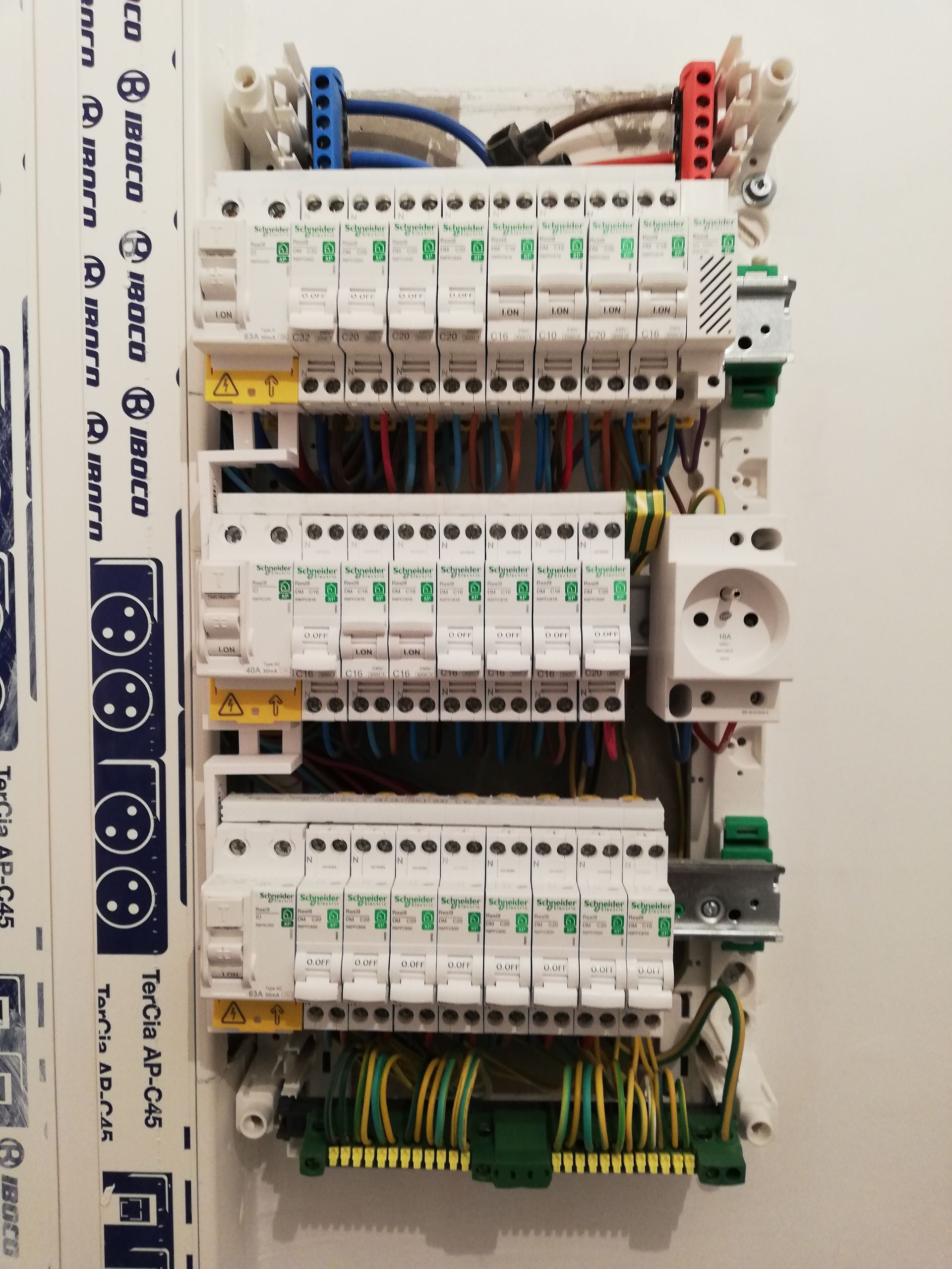 Tableau électrique avec disjoncteurs modulaires et câblage apparent.