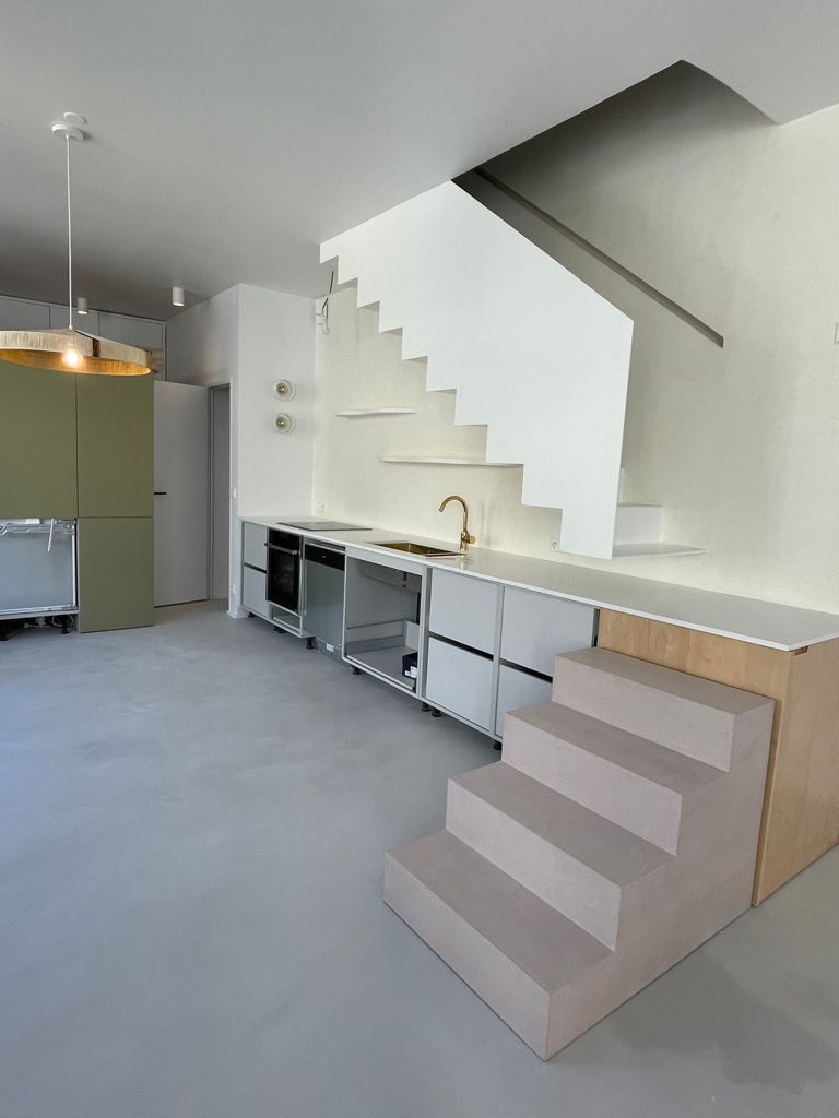 Cuisine moderne avec escalier blanc, placards gris et vert kaki.
