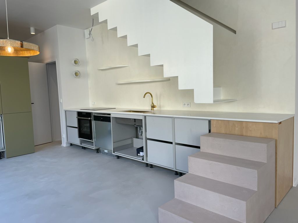 Cuisine en cours de rénovation avec éléments non finalisés intégrés sous un escalier.