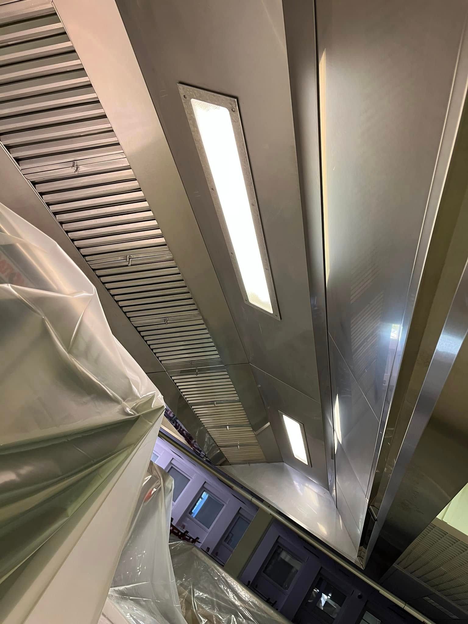 Vue en biais du plafond d'une cuisine commerciale avec hottes de ventilation.