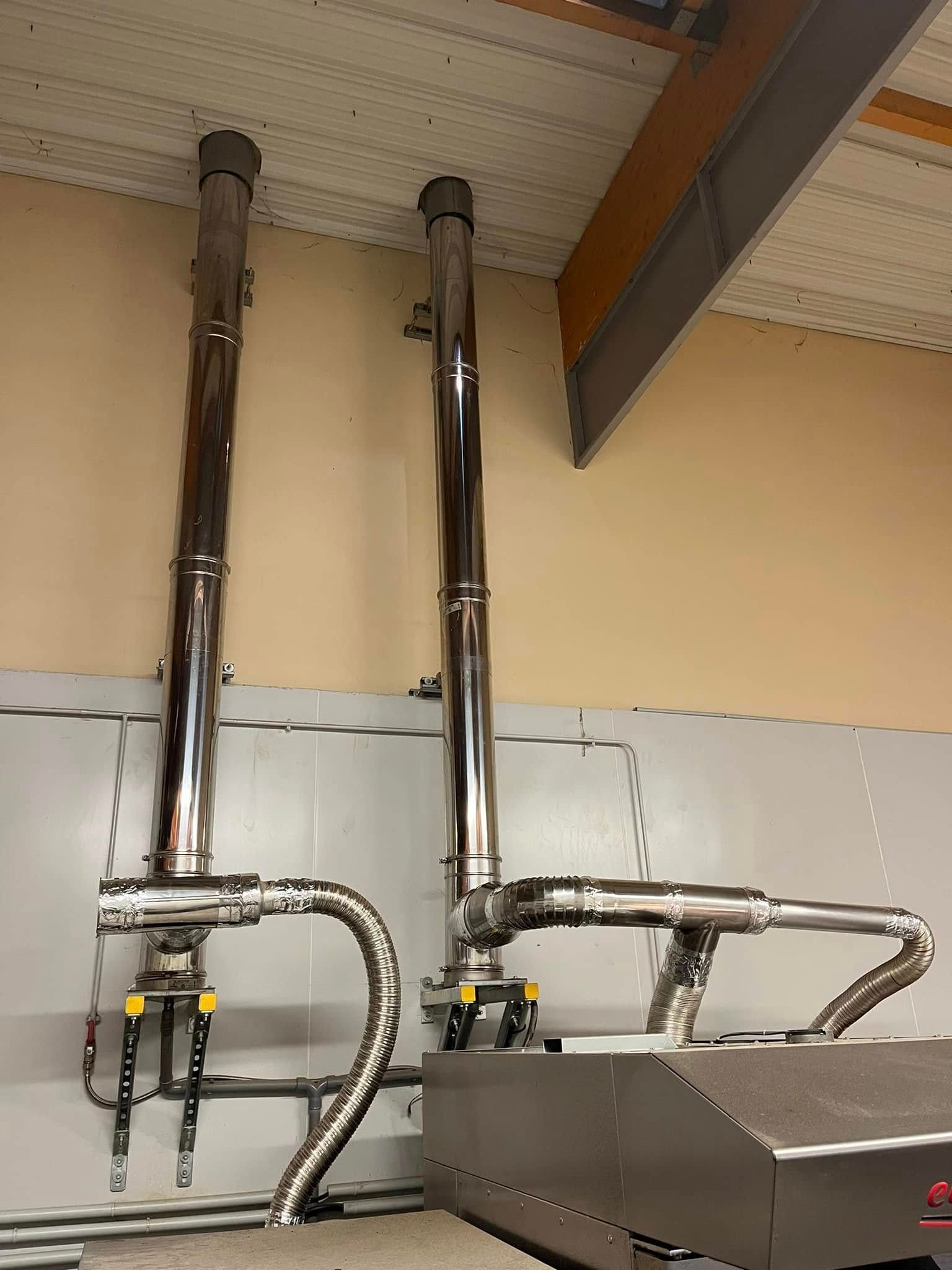 Deux cheminées d'échappement en acier inoxydable s'élèvent d'un équipement industriel.