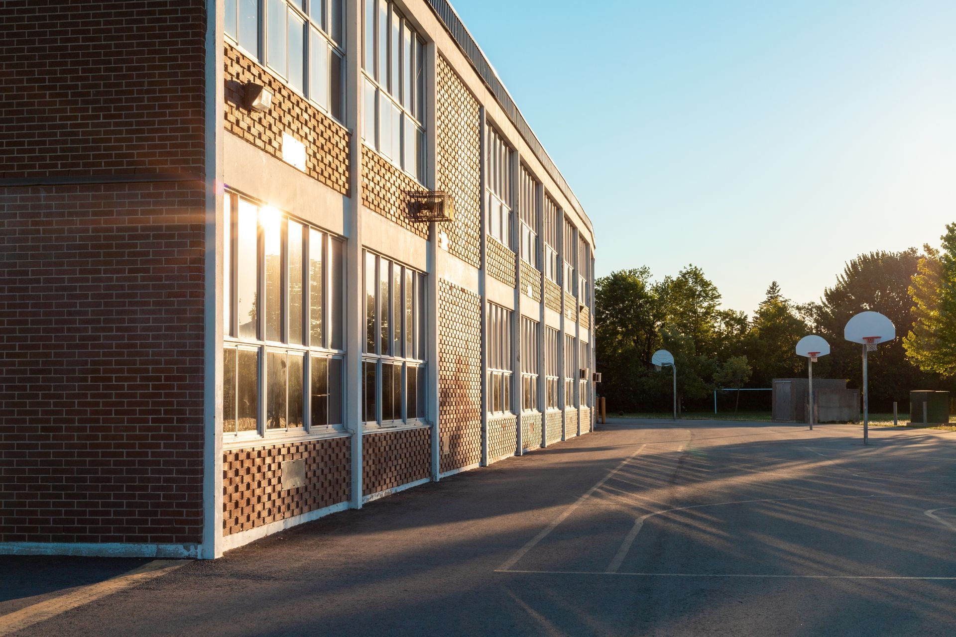 Le côté d'un bâtiment scolaire en briques, orné de panneaux à motifs quadrillés et de grandes fenêtres.