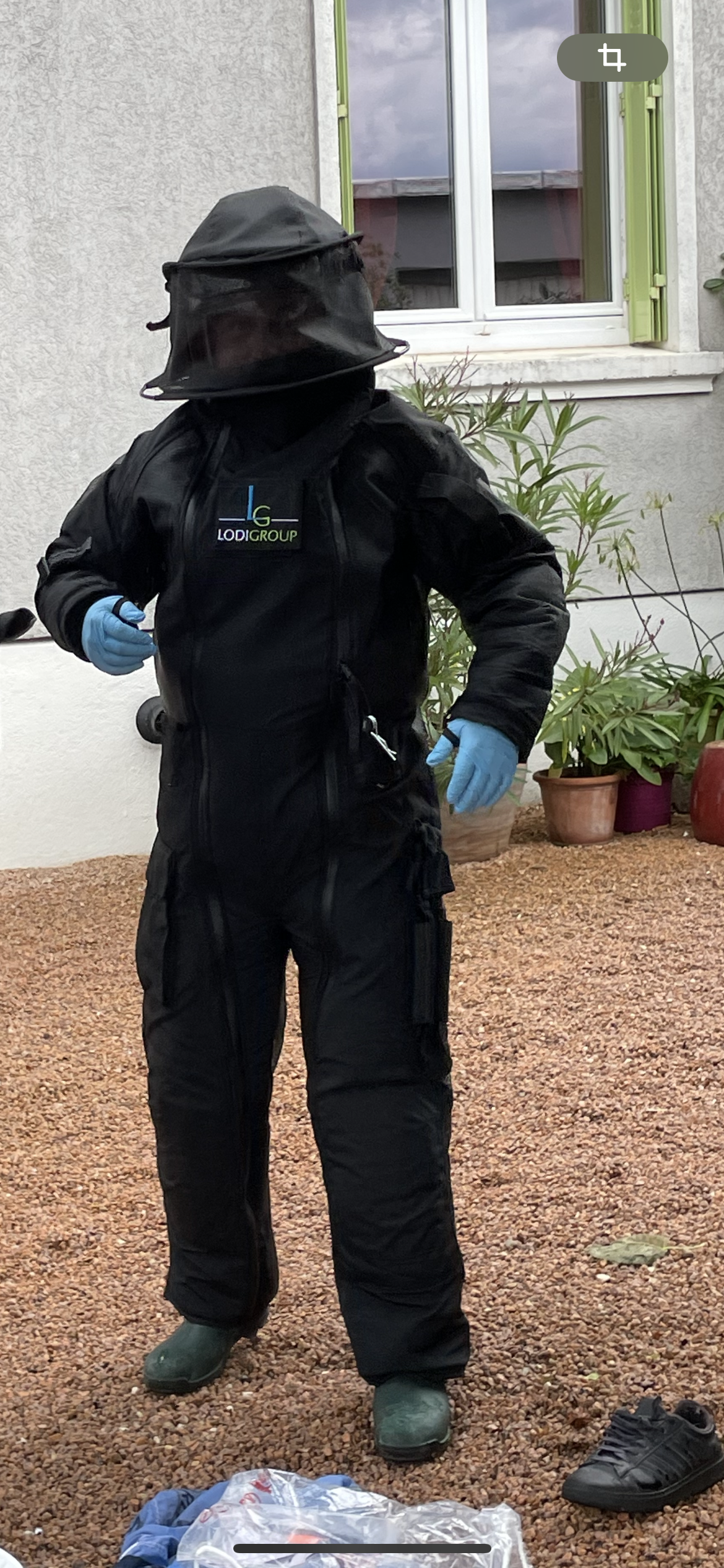 Un membre de l'équipe de DMAIR vêtu d'une combinaison d'apiculteur avec une capuche en filet et des gants bleus.