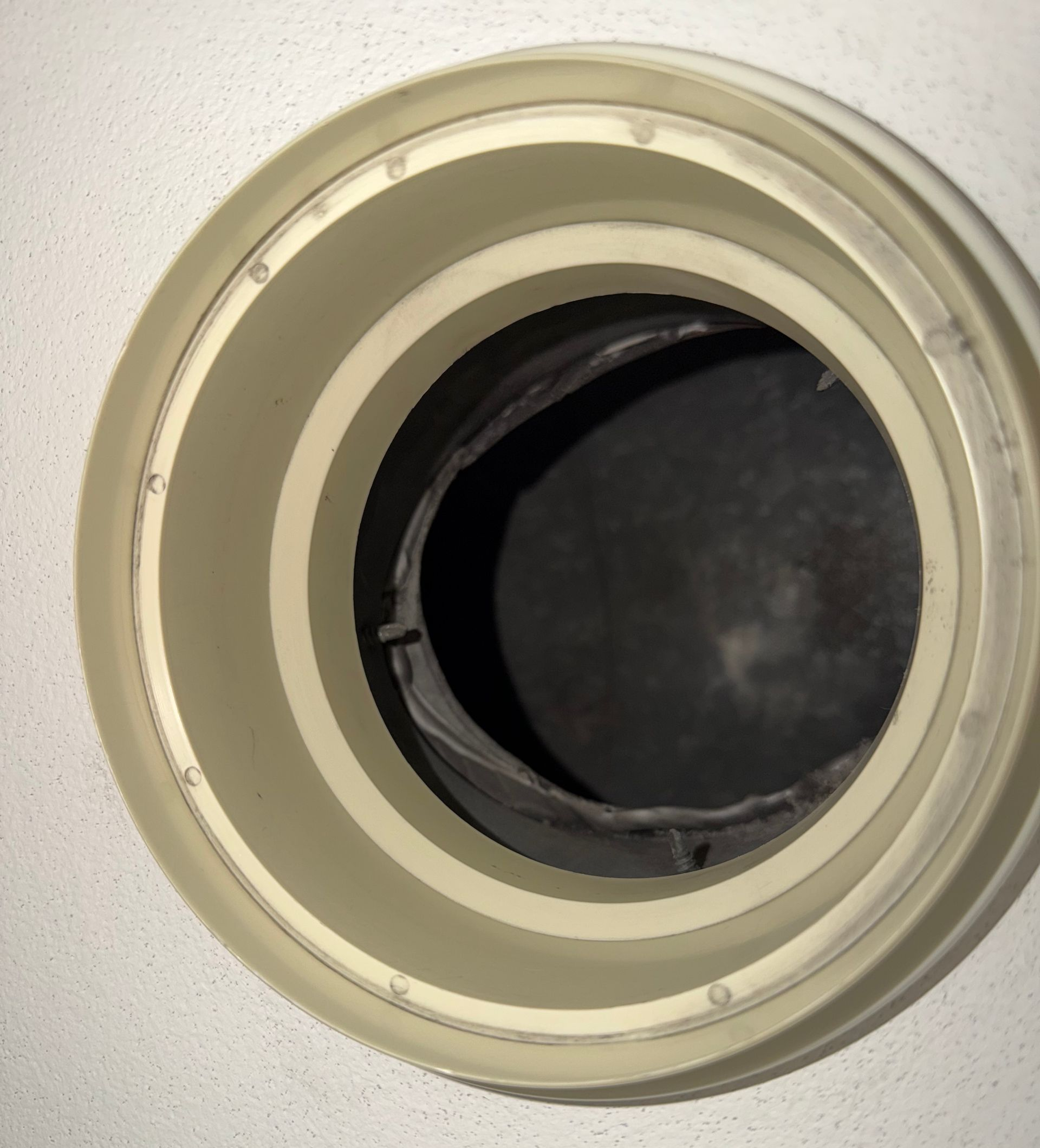 Gros plan d'une grille d'aération murale circulaire ouverte et propre.