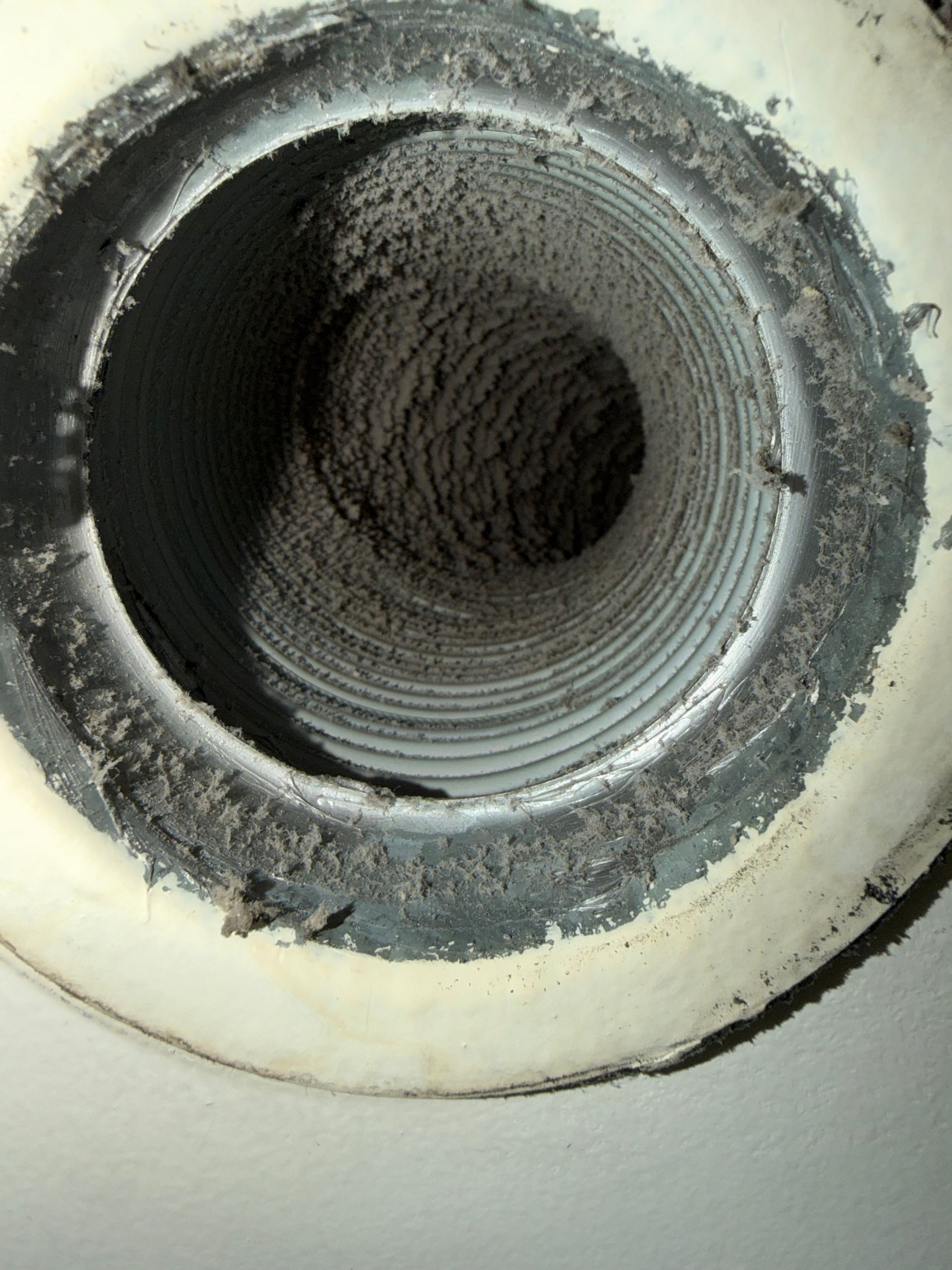 Gros plan sur l'intérieur d'une grille d'aération cylindrique fortement recouverte d'une épaisse couche de poussière.