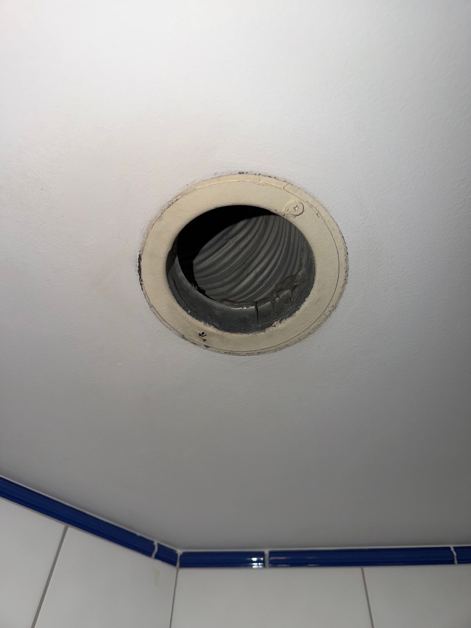 Une grille d'aération ronde et blanche au plafond après nettoyage.