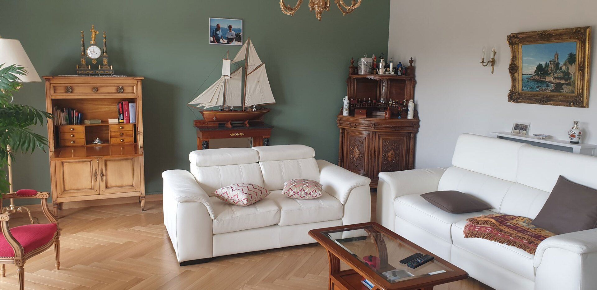 Salon aménagé avec une maquette de bateau et un mur vert
