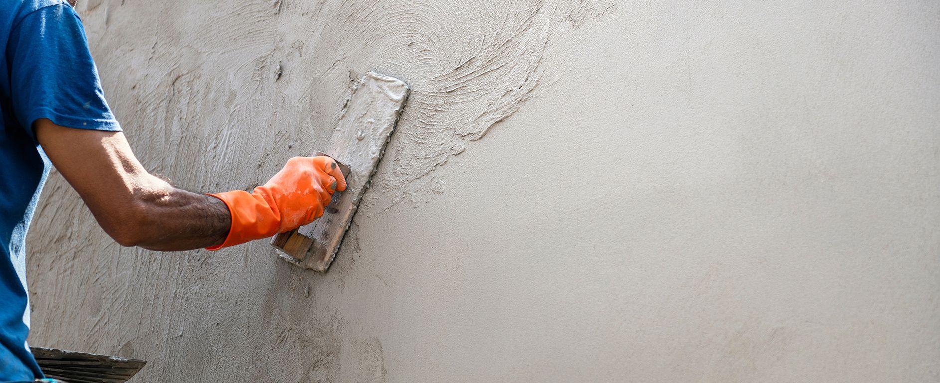 Main d'ouvrier apposant du ciment sur un mur