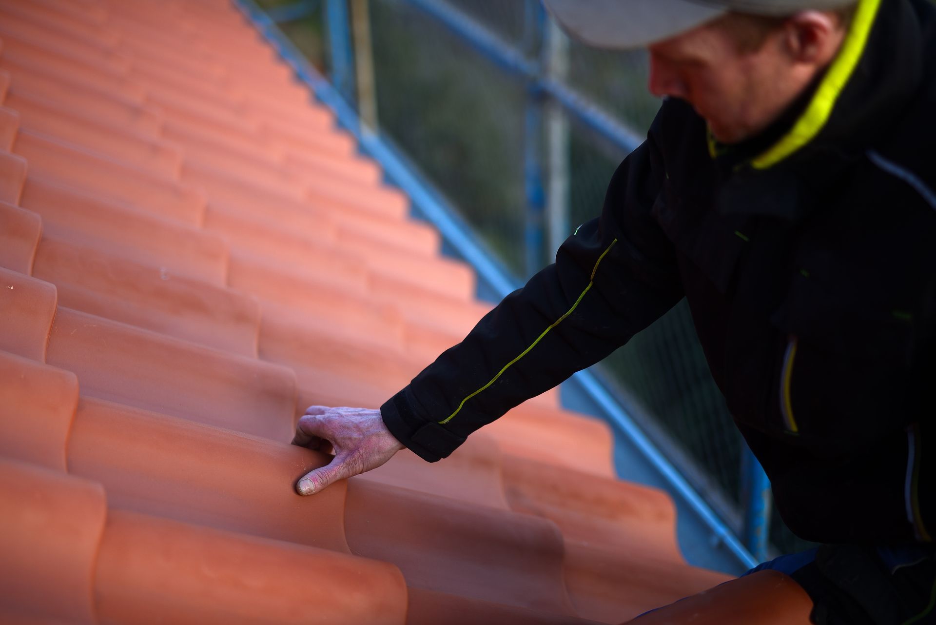 Personne inspectant des tuiles de toit en terre cuite.