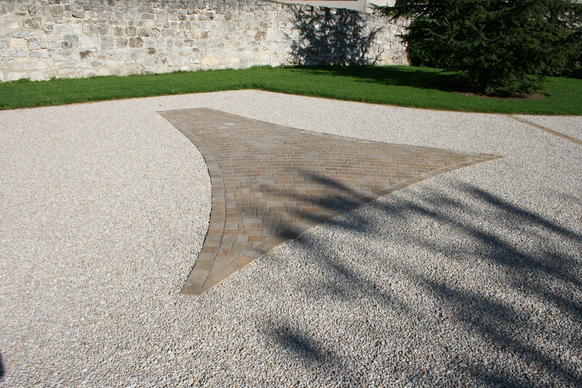 Allée en pierre avec une section en briques et entourée de gravier, d'herbe et d'un muret en pierre