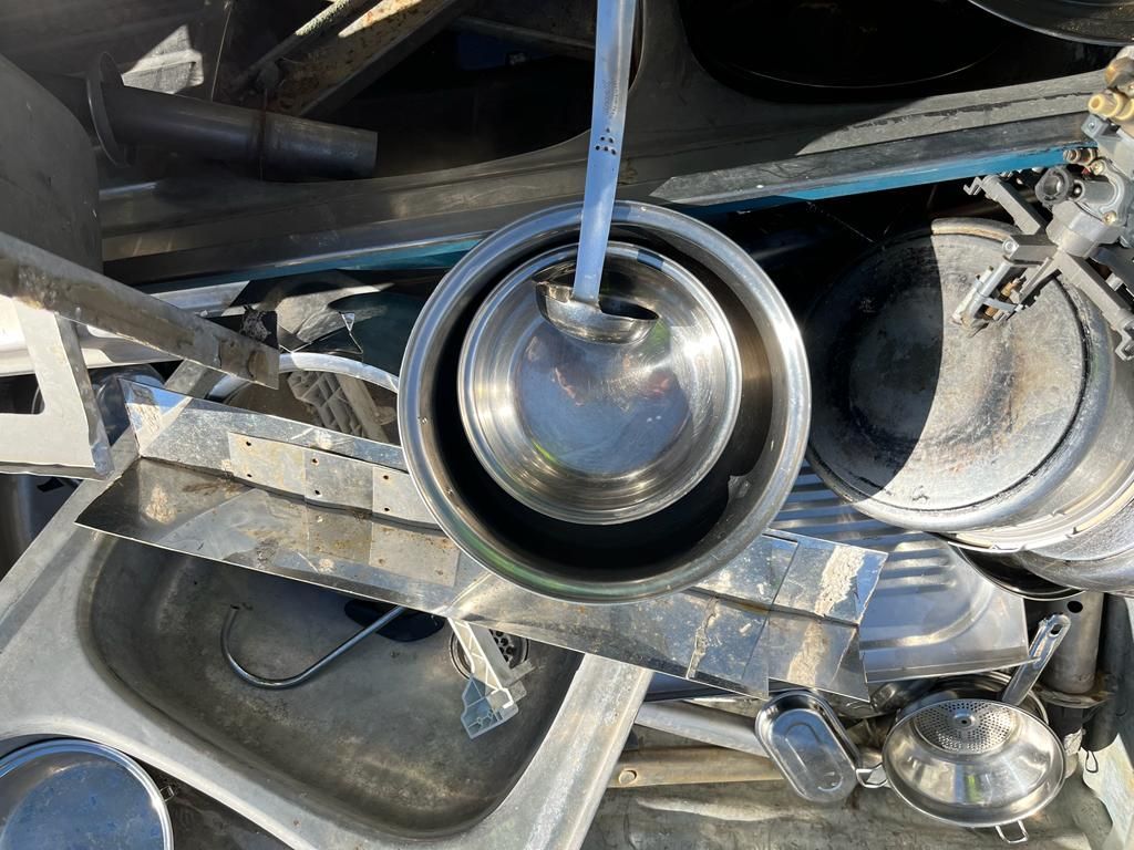 Una pila de ollas y sartenes de acero inoxidable con un cucharón en el medio.