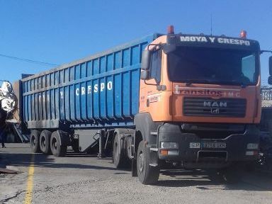 Un camión con remolque azul está estacionado al costado de la carretera.