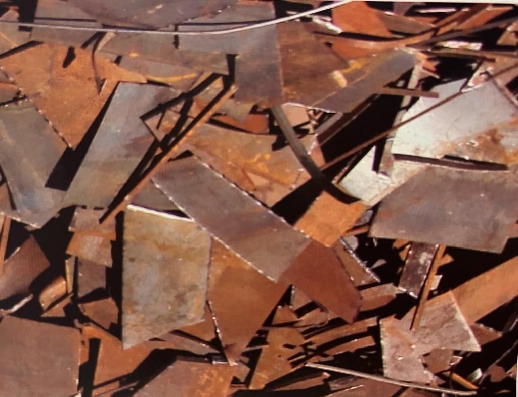 Una pila de piezas de metal oxidadas con una sombra en el suelo.