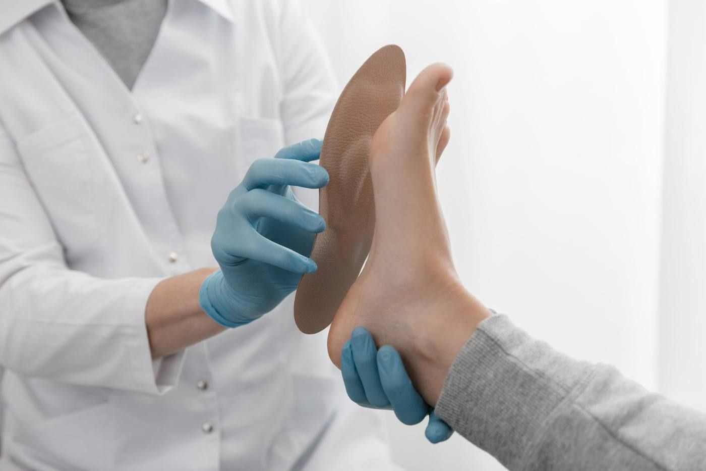 Médico examinando el pie de un paciente con guantes azules en un entorno médico bien iluminado.