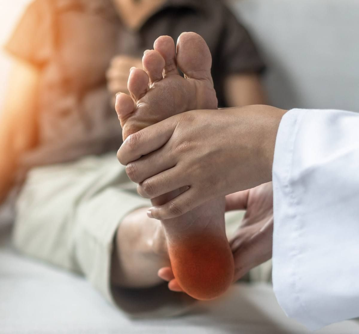 Masaje de pies en curso, con un talón rojo y una persona acostada en una cama.