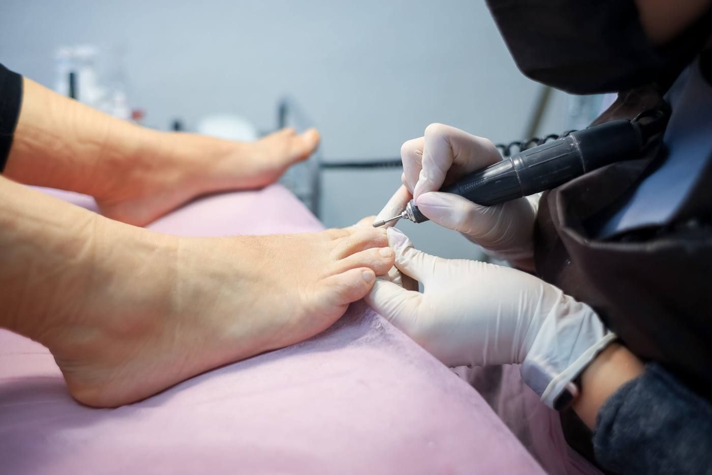 Un podólogo está cortando las uñas de los pies de un paciente con una herramienta especial.