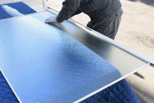 Personne étalant un tissu sur une table à l'aide d'un outil métallique plat à l'extérieur.