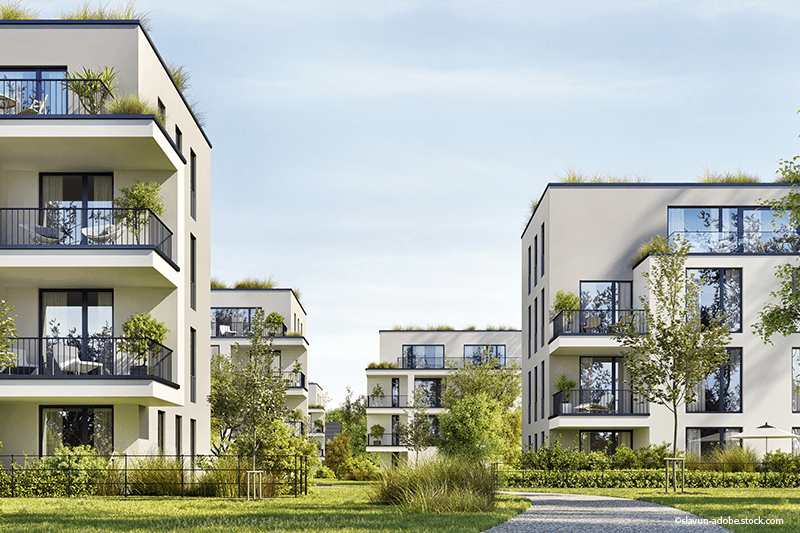 Moderne Apartmentgebäude mit Balkonen und Grünanlagen an einem sonnigen Tag