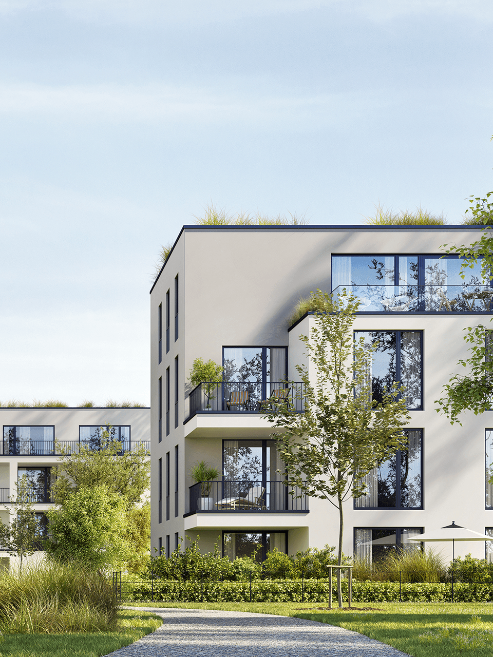 Moderne Wohngebäude mit Balkonen und Bäumen in einem begrünten Innenhof unter klarem Himmel