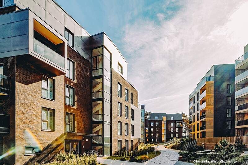 Moderne Apartmentgebäude mit Balkonen und einem begrünten Innenhof unter einem bewölkten Himmel
