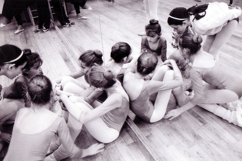 Un grupo de chicas jóvenes están sentadas en el suelo frente a un espejo.