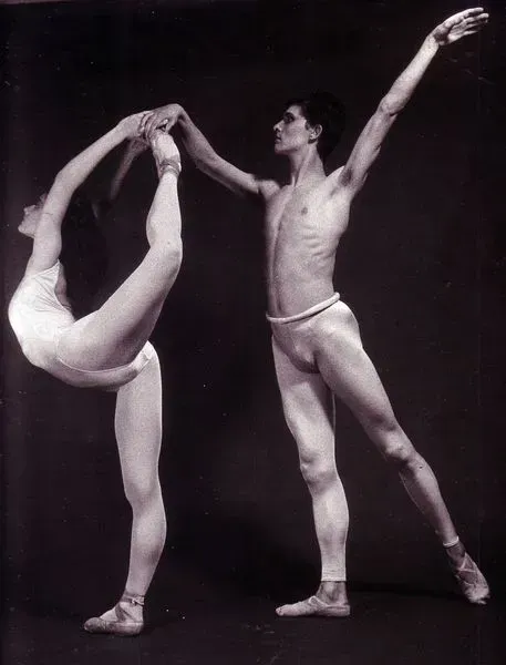Bailarines de ballet en una fotografía en blanco y negro. La mujer está inclinada hacia atrás sujetando su pie, el hombre la sostiene del brazo.