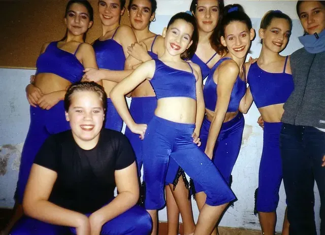 Grupo de bailarines con trajes azules, posando en un estudio de danza.