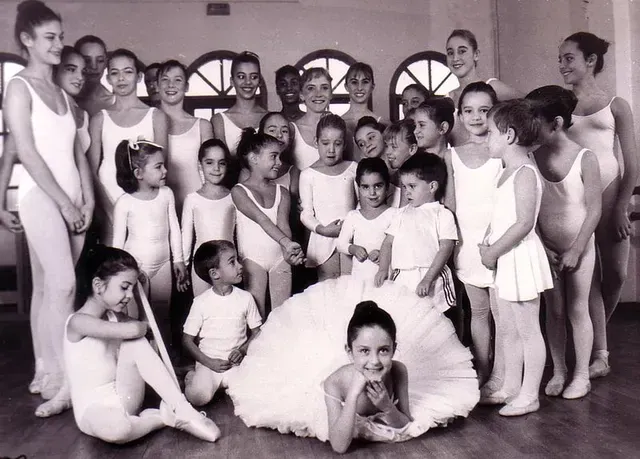 Retrato de una clase de ballet: Jóvenes estudiantes con leotardos y tutús, posando en un estudio de danza.