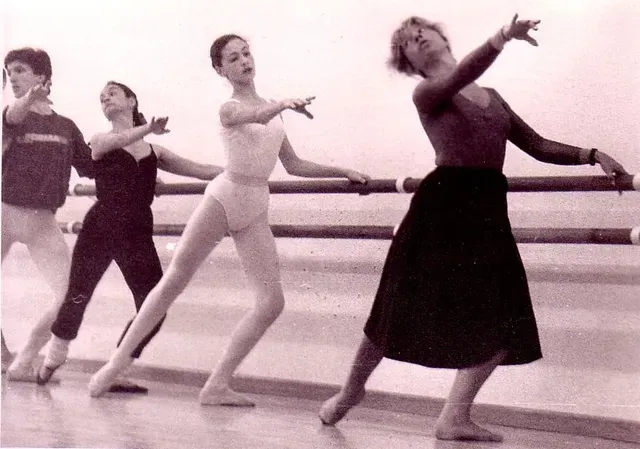 Bailarinas de ballet en la barra, haciendo ejercicio. Bailarinas con diferentes atuendos, con los brazos extendidos. Estudio interior.