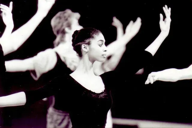 Bailarinas de ballet en un estudio, con los brazos levantados en poses gráciles. Leotardo negro.