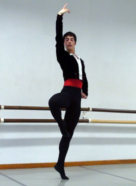 Un hombre está de pie sobre una pierna en un estudio de baile.